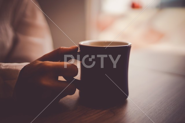 ホットコーヒーを飲む女性と手