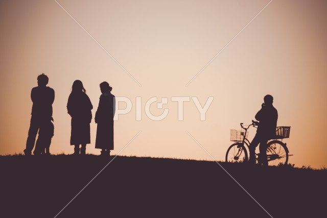 夕暮れの丘に座る人々のシルエット
