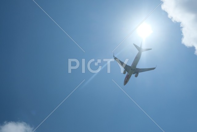 真夏の太陽と旅客機の離陸