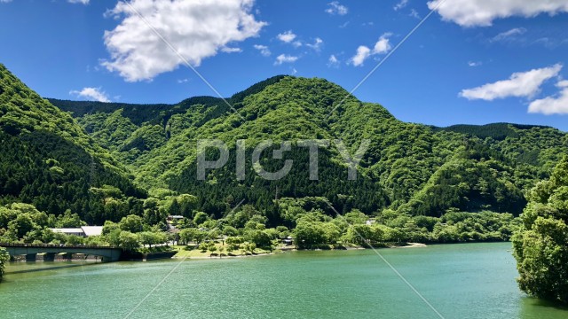 新緑の山並みとエメラルドグリーンの湖畔の風景