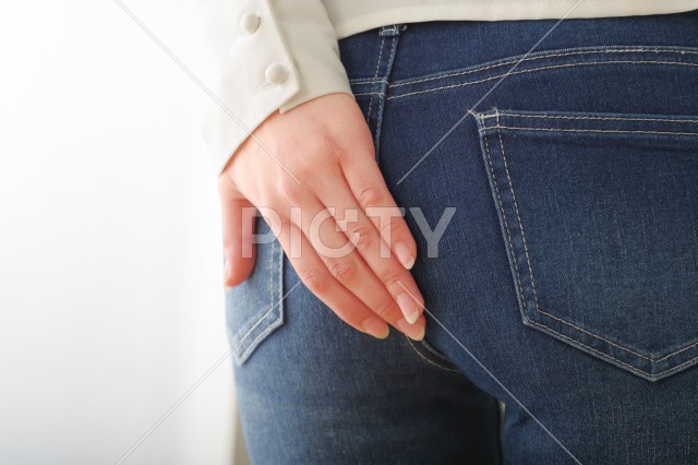 お尻を手で押さえる女性