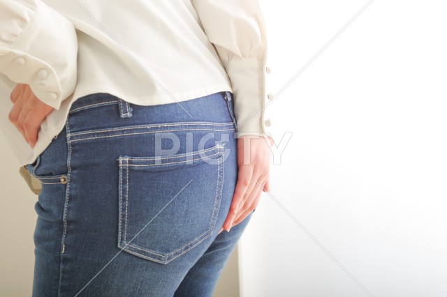 お尻を手で押さえる女性